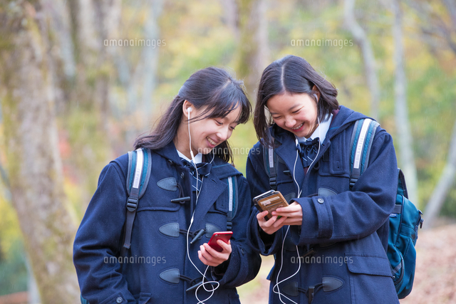 スマホで音楽を楽しむ女子中学生2人 の写真素材 イラスト素材 アマナイメージズ