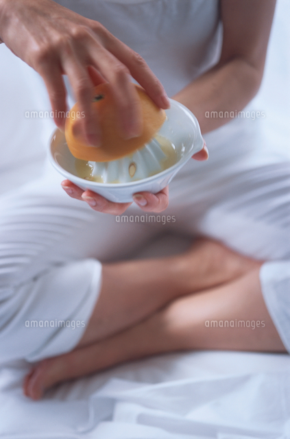 座ってオレンジ絞る日本人女性 の写真素材 イラスト素材 アマナイメージズ