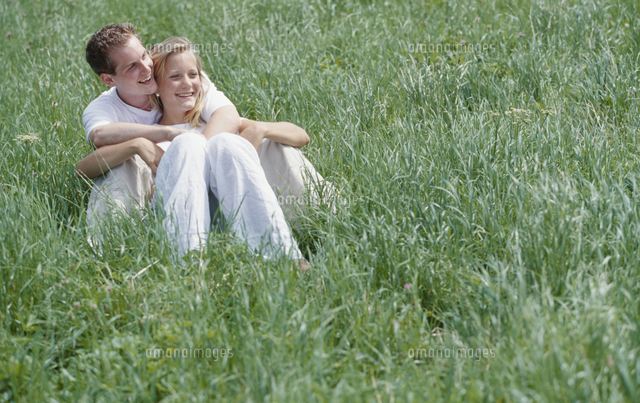 原っぱで座っている外国人カップル の写真素材 イラスト素材 アマナイメージズ