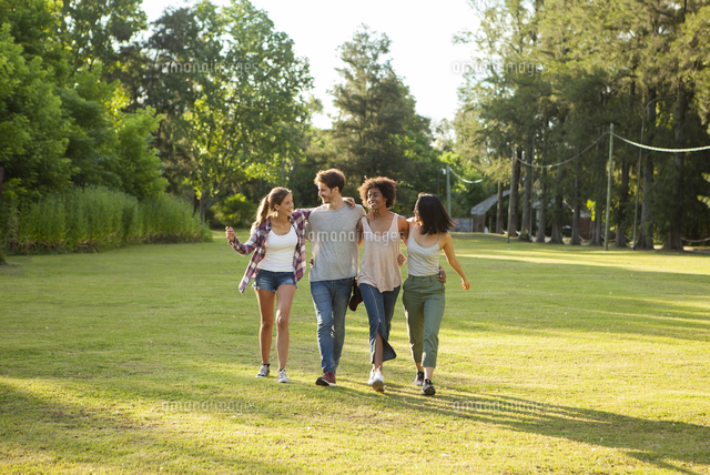 Happy young friends walking together in park[11001072523]の写真素材・イラスト素材 ...