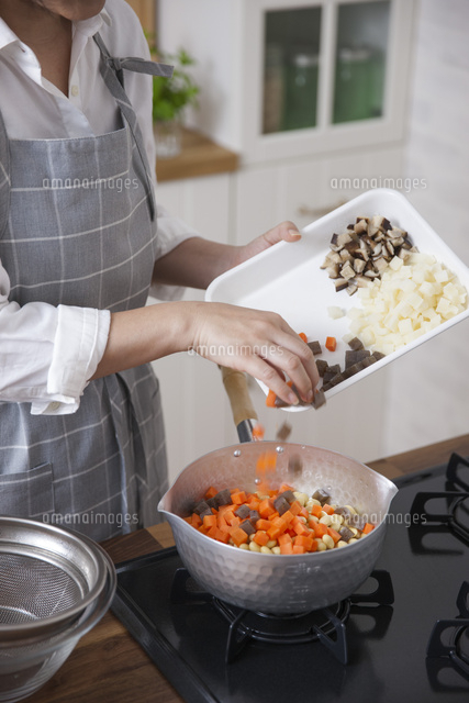 鍋に角切りにした具材を入れる女性 の写真素材 イラスト素材 アマナイメージズ