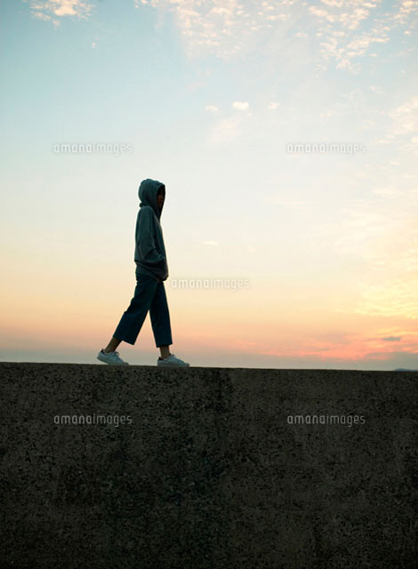 堤防を歩く女性 の写真素材 イラスト素材 アマナイメージズ