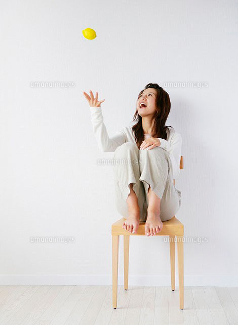 椅子に座ってレモンを上に投げる日本人女性 の写真素材 イラスト素材 アマナイメージズ