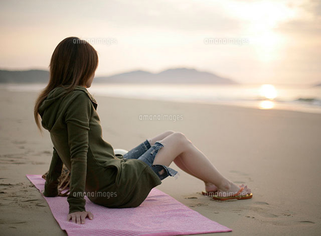 夕日と砂浜に座る女性 の写真素材 イラスト素材 アマナイメージズ