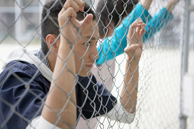 フェンス越しに見つめる男性 の写真素材 イラスト素材 アマナイメージズ