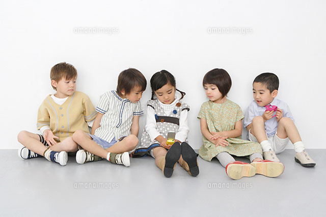 携帯電話を覗き込む子供達 の写真素材 イラスト素材 アマナイメージズ
