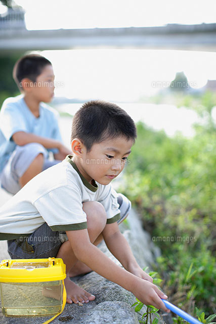 土手にしゃがむ男の子 の写真素材 イラスト素材 アマナイメージズ