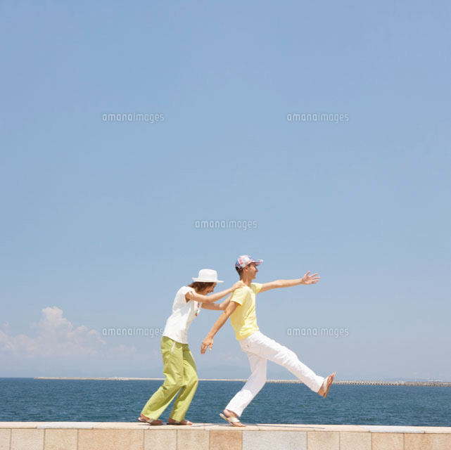 防波堤を歩くカップル の写真素材 イラスト素材 アマナイメージズ