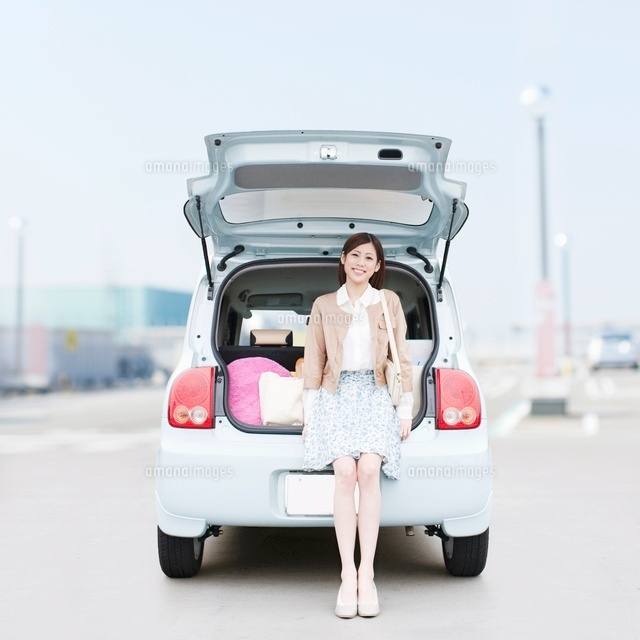 車のトランクに座って微笑む女性 の写真素材 イラスト素材 アマナイメージズ