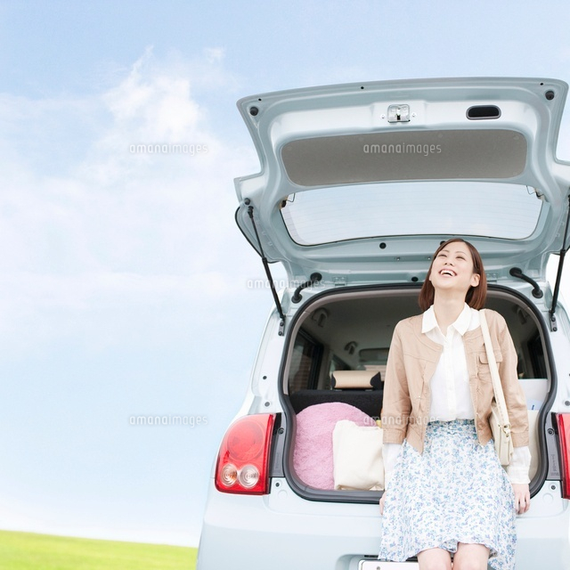 車のトランクに座って見上げる女性 の写真素材 イラスト素材 アマナイメージズ