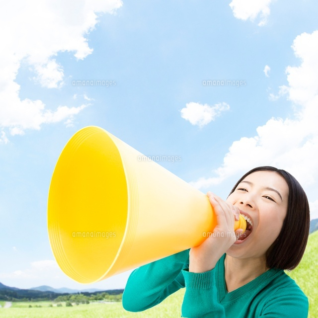草原でメガホンを持って叫ぶ女性 の写真素材 イラスト素材 アマナイメージズ
