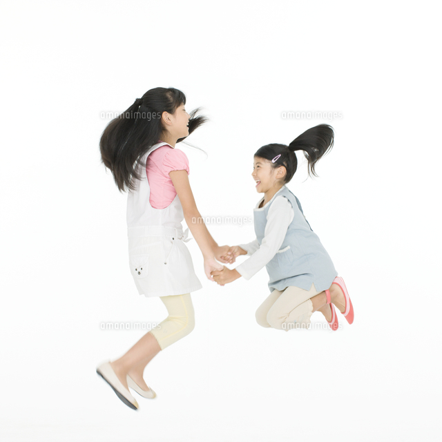 手を繋いでジャンプする2人の女の子 の写真素材 イラスト素材 アマナイメージズ