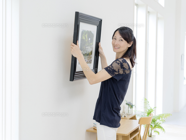 絵画を壁に飾る女性 の写真素材 イラスト素材 アマナイメージズ