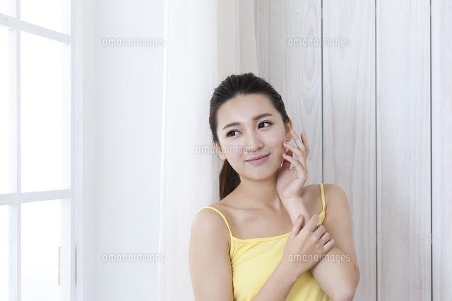 Young woman in a yellow dress hands on her face and smiling looking ...