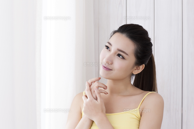 Young woman in a yellow dress hands on her face and smiling looking ...