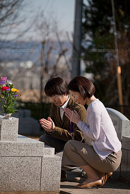 カジュアルウェアでお墓の前で手を合わせる夫婦 の写真素材 イラスト素材 アマナイメージズ