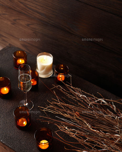 Lit candles and glasses of champagne on wooden table[11015271091]の写真素材