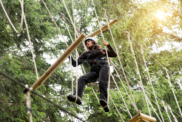 Teenage girl on high rope course[11015332344]の写真素材・イラスト素材｜アマナイメージズ