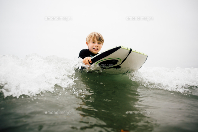 Young boy bodyboarding in sea[11015333334]の写真素材・イラスト素材｜アマナイメージズ