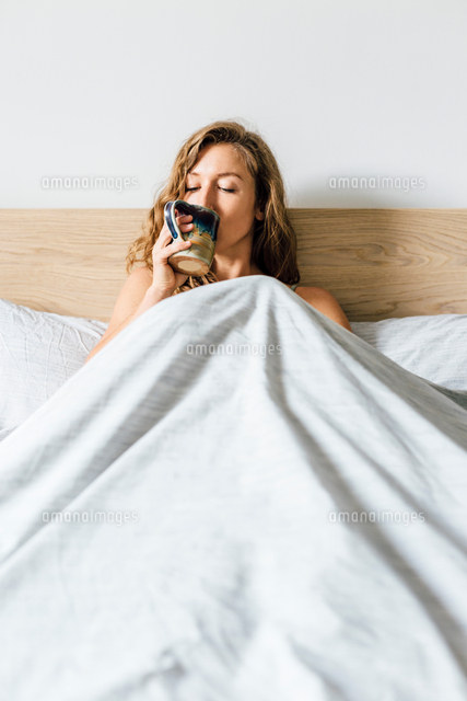 Young Woman Sitting Up In Bed Drinking Coffee の写真素材 イラスト 素材 アマナイメージズ