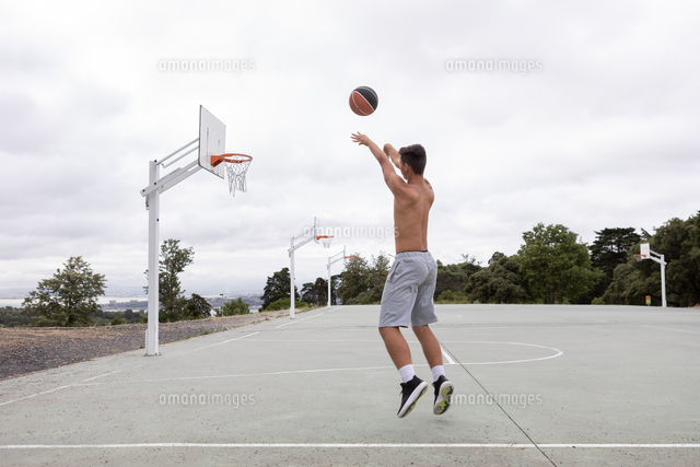Male Teenage Basketball Player Jumping And Throwing Ball Toward Basketball Hoop の写真素材 イラスト素材 アマナイメージズ