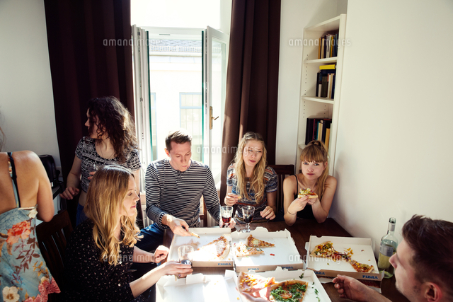 Group Of Friends Chatting Over Drinks And Pizza At Home の写真素材 イラスト素材 アマナイメージズ