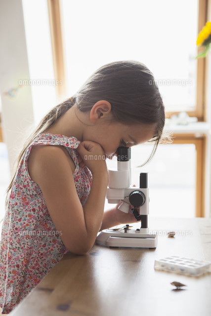 Side View Of Curious Girl Looking Into Microscope On Table At Home の写真素材 イラスト素材 アマナイメージズ