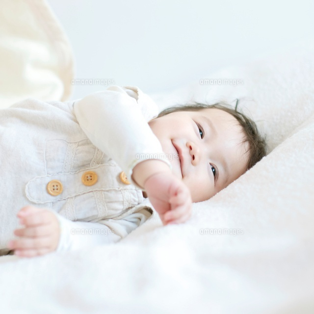 布団の上で微笑む赤ちゃん の写真素材 イラスト素材 アマナイメージズ