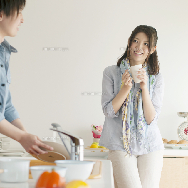 キッチンで洗い物をする男性とコーヒーを飲む女性 の写真素材 イラスト素材 アマナイメージズ