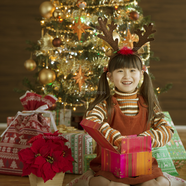 クリスマスプレゼントを開ける女の子 の写真素材 イラスト素材 アマナイメージズ