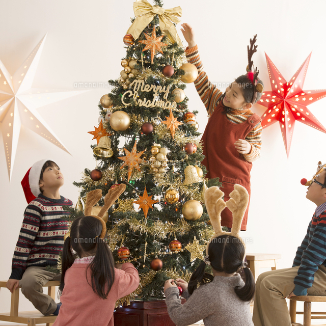 クリスマスツリーに飾り付けをする子供達 の写真素材 イラスト素材 アマナイメージズ