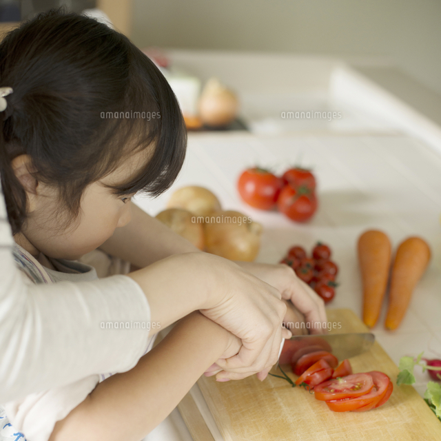 母親に野菜の切り方を教えてもらう女の子 の写真素材 イラスト素材 アマナイメージズ
