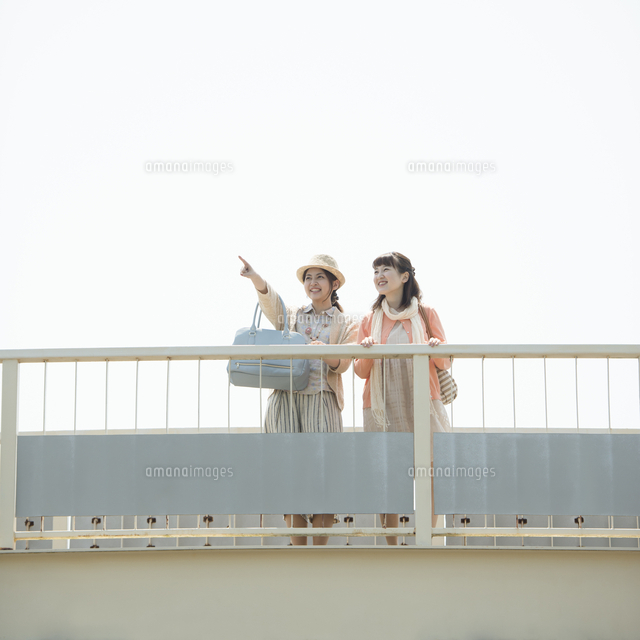 歩道橋の上から景色を眺める2人の女性 の写真素材 イラスト素材 アマナイメージズ