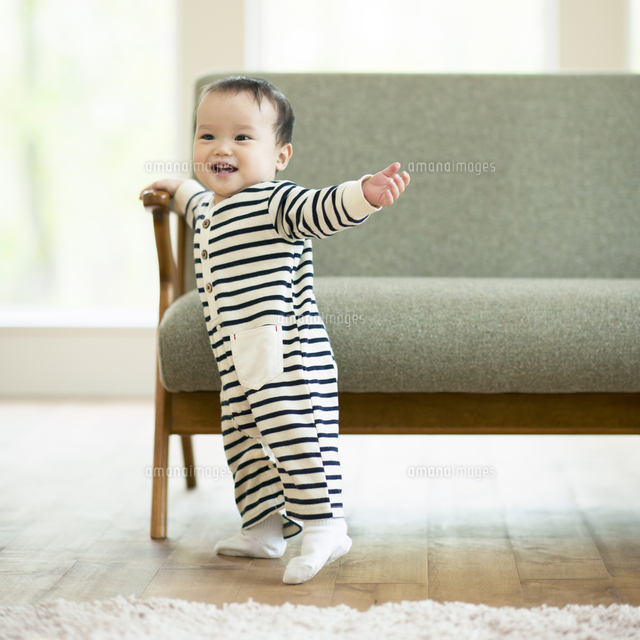 ソファーでつかまり立ちをする赤ちゃん の写真素材 イラスト素材 アマナイメージズ