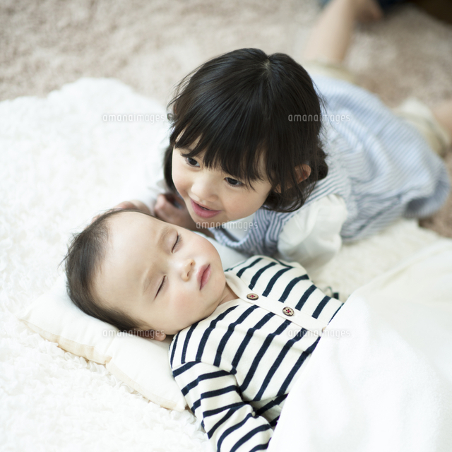 寝ている赤ちゃんに寄り添う女の子 の写真素材 イラスト素材 アマナイメージズ