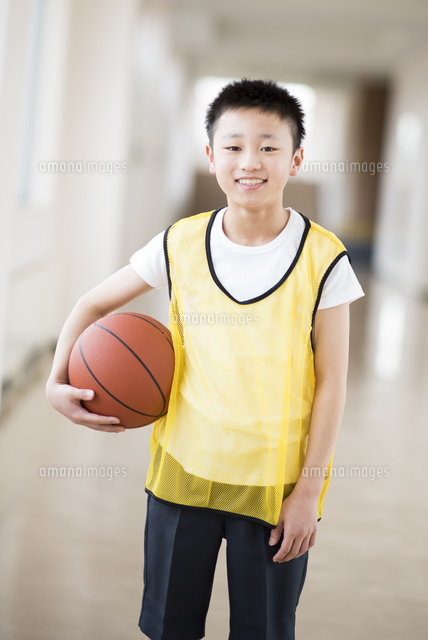 廊下でバスケットボールを持ち微笑む小学生 の写真素材 イラスト素材 アマナイメージズ
