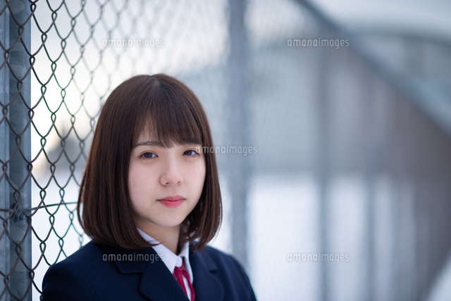 フェンスに寄りかかる女子学生 の写真素材 イラスト素材 アマナイメージズ