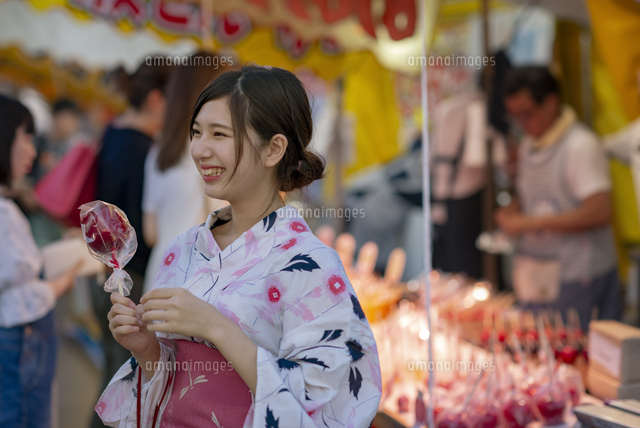 屋台の前でりんご飴を持つ女性 の写真素材 イラスト素材 アマナイメージズ