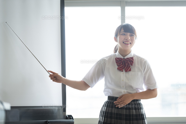 プロジェクタースクリーンの前で指示棒を持つ女子学生 の写真素材 イラスト素材 アマナイメージズ