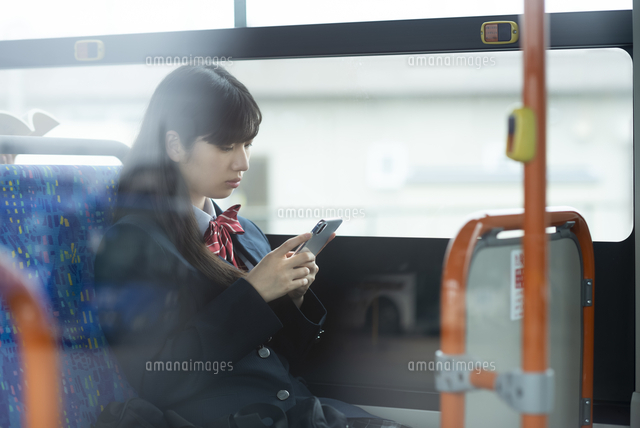 バスの中でスマホを見る女子学生 の写真素材 イラスト素材 アマナイメージズ