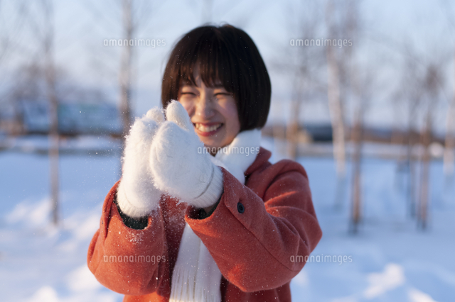 手袋についた雪をはらい落とす若い女性 の写真素材 イラスト素材 アマナイメージズ