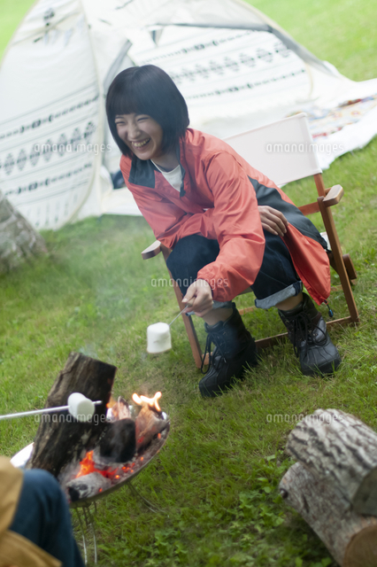 焚き火でマシュマロを焼くカップル の写真素材 イラスト素材 アマナイメージズ