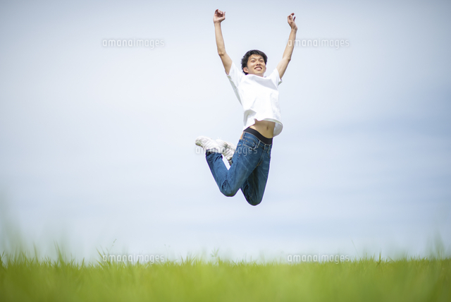 草原でジャンプする男性 の写真素材 イラスト素材 アマナイメージズ