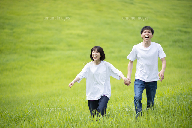 草原で手をつなぐカップル の写真素材 イラスト素材 アマナイメージズ