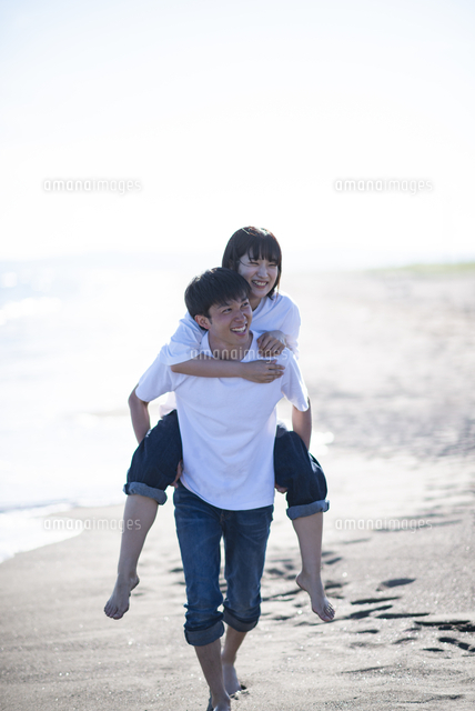 浜辺で恋人を背負う男性 の写真素材 イラスト素材 アマナイメージズ