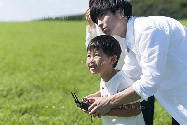 草原でドローンを操縦する親子 の写真素材 イラスト素材 アマナイメージズ