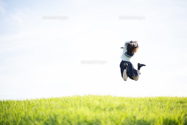 草原でジャンプする制服姿の女子学生 の写真素材 イラスト素材 アマナイメージズ