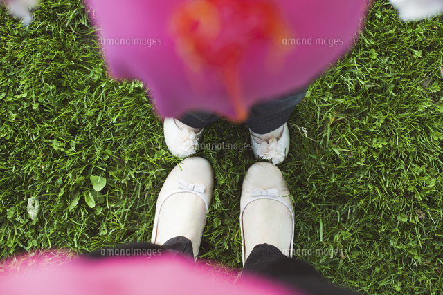 High angle view of feet of mother and daughter in grass 