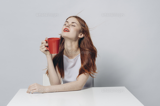 Caucasian woman sitting at windy table holding red cup[11018098030]の写真 ...