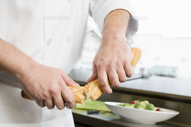 Male chef breaking bread in half[11029015596]の写真素材・イラスト素材｜アマナイメージズ